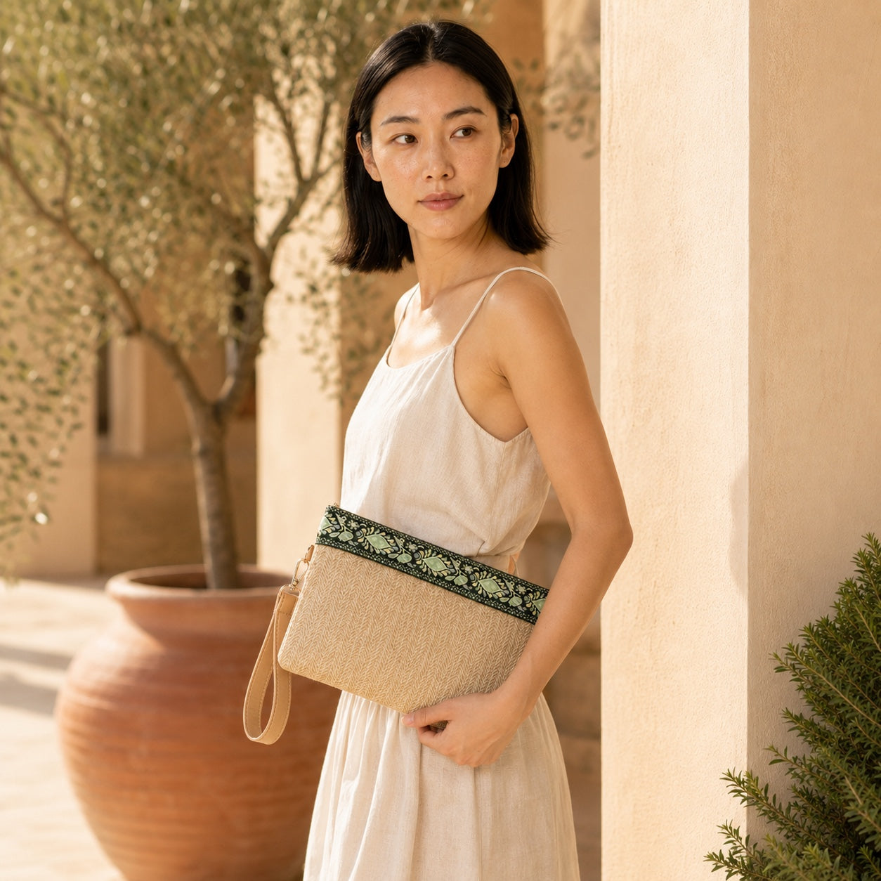 Model wearing the Valldemossa - Straw Clutch in Green And Beige, side view